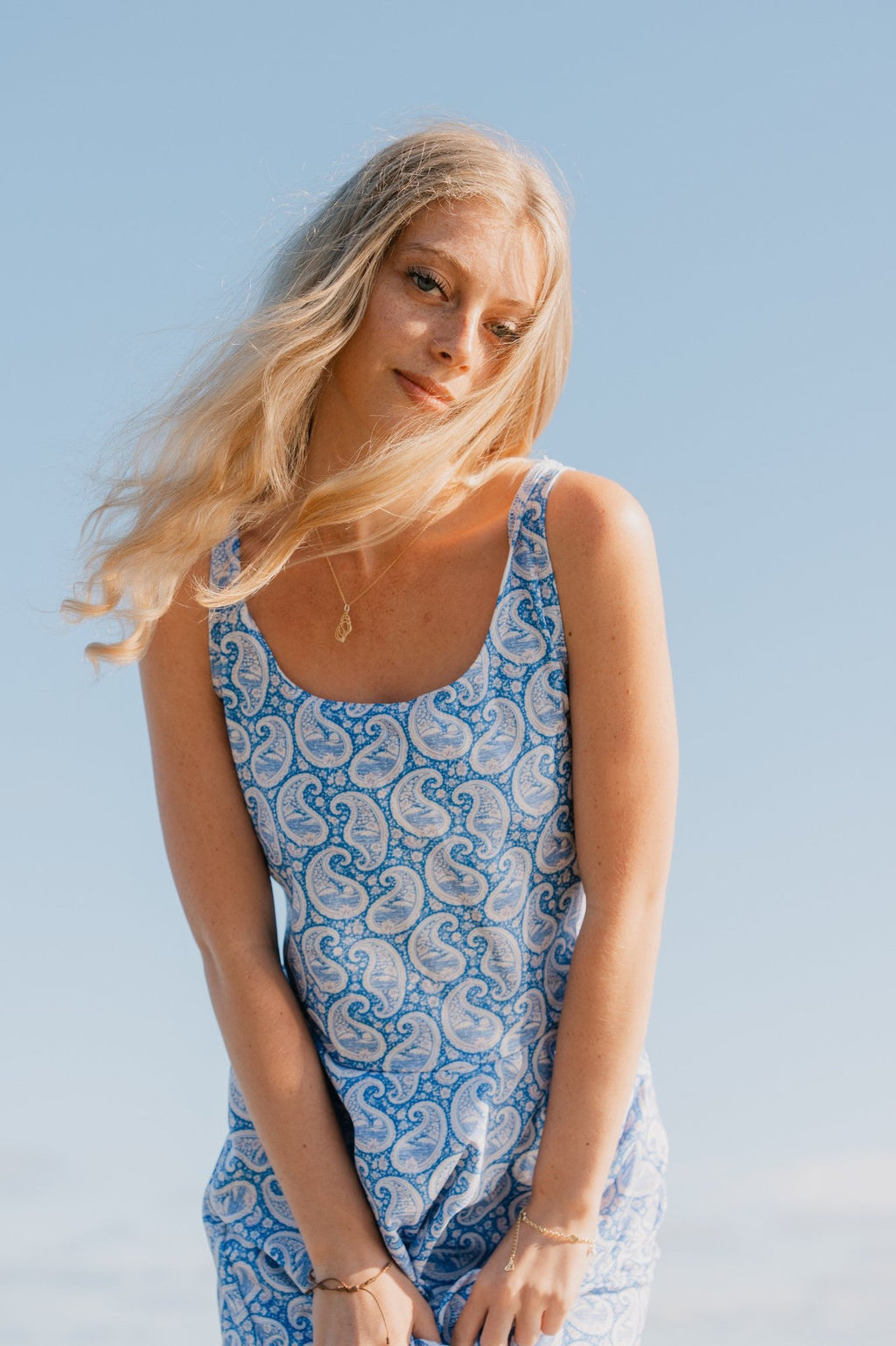 Woman wearing a blue and white patterned dress against a clear blue sky.