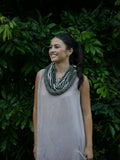 Model in a soft Kahoʻolawe-toned sleeveless linen midi dress with round neckline and pockets, wearing lei, photographed on a Hilo farm.