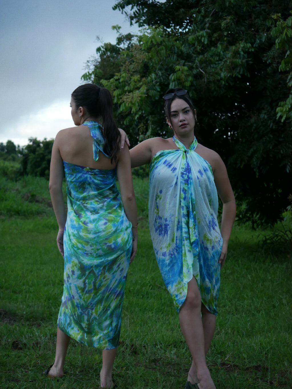 Models in green, blue, and navy shibori tie-dye silk wrap scarves, tied as pareo-style dresses, photographed at Olson Keolanui Farms in Hilo.