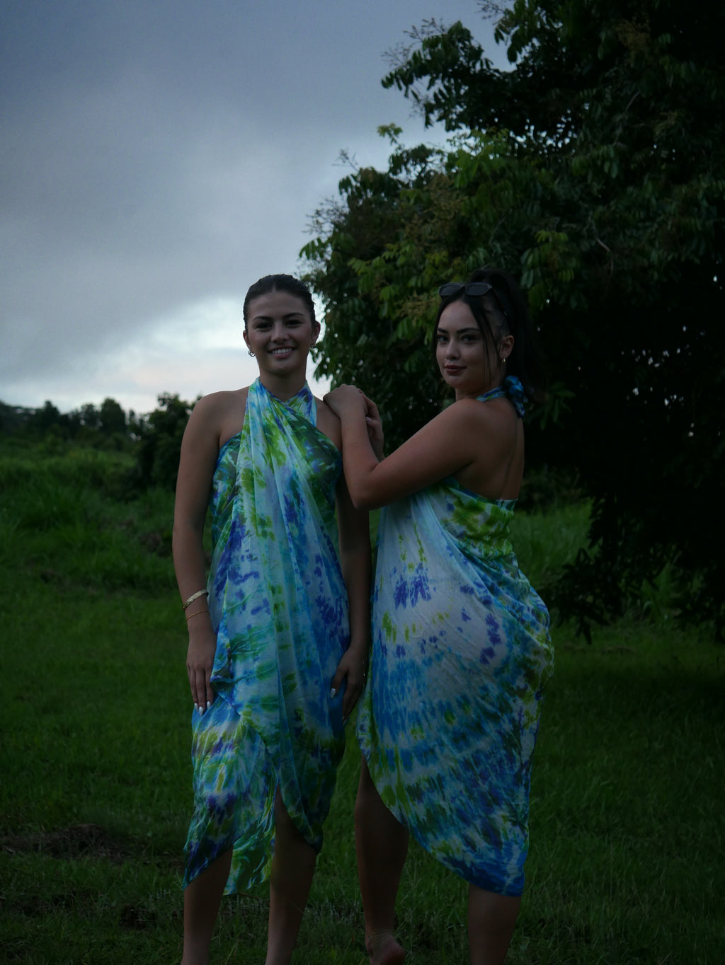 Models in green, blue, and navy shibori tie-dye silk wrap scarves, tied as pareo-style dresses, photographed at Olson Keolanui Farms in Hilo.