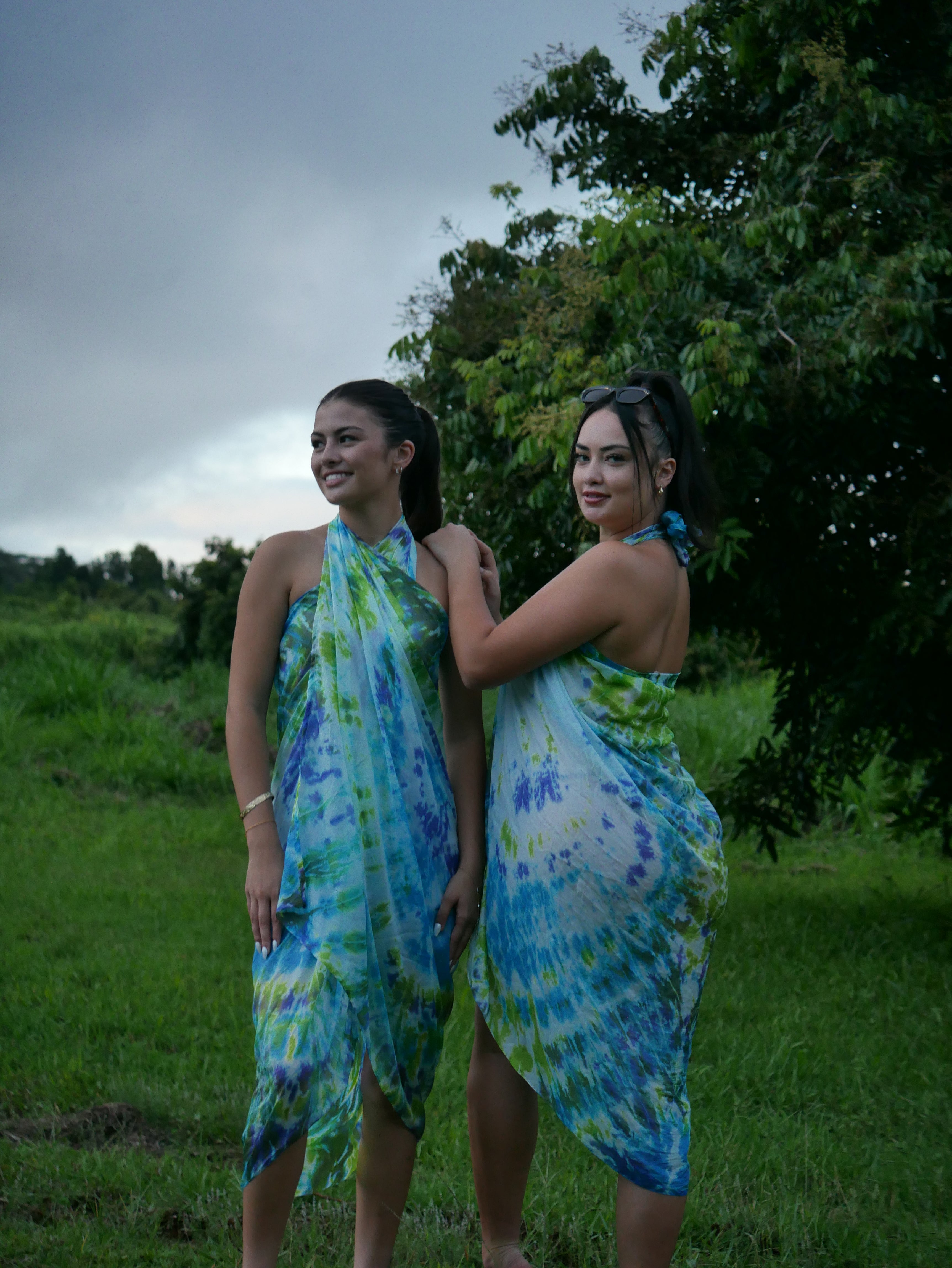 Models in green, blue, and navy shibori tie-dye silk wrap scarves, tied as pareo-style dresses, photographed at Olson Keolanui Farms in Hilo.