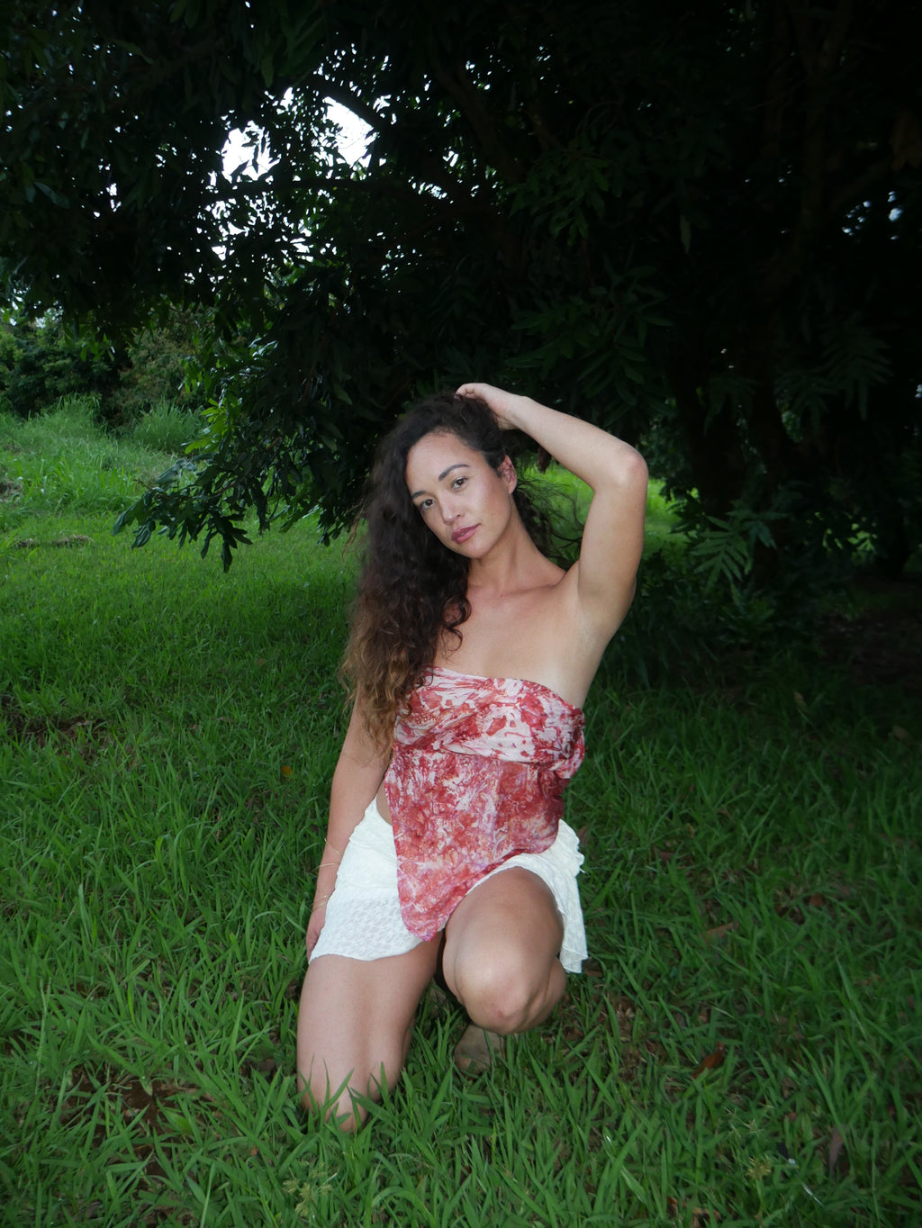 Model in a warm red shibori tie-dye silk wrap scarf, photographed at Olson Keolanui Farms in Hilo.