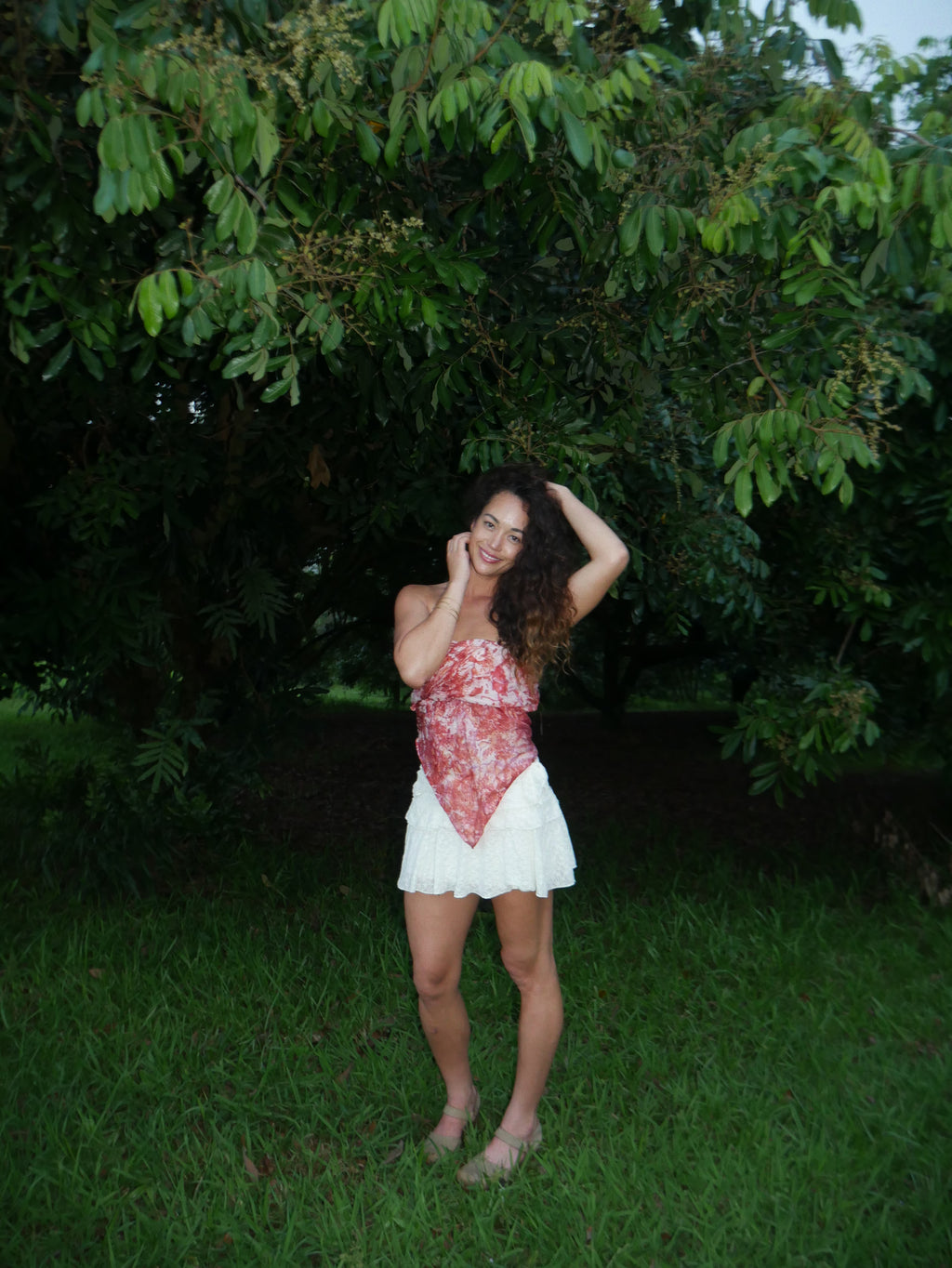 Model in a warm red shibori tie-dye silk wrap scarf, photographed at Olson Keolanui Farms in Hilo.